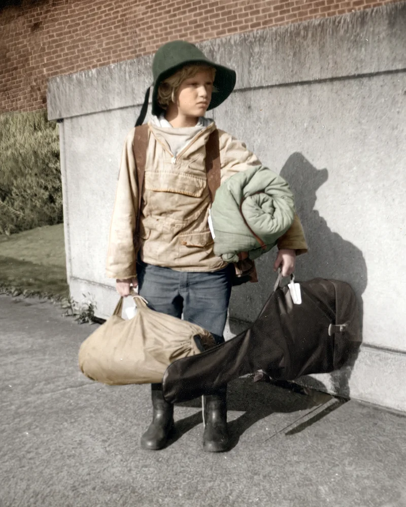 Hand-coloured image of Django Bates as a boy in hat and wellington boots about to embark upon an expedition